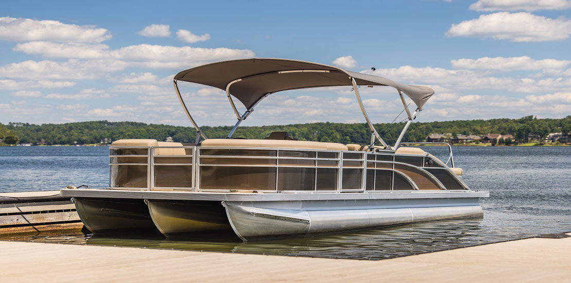 A pontoon boat at a dock on a lake